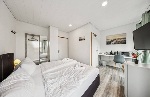 Wilhelmshaven Hotel | Cozy double room, flat-screen TV, and modern bathroom with shower. Ideal for couples and short stays – enjoy a relaxed atmosphere with warm wood accents and coastal charm.