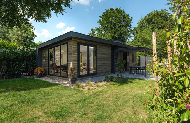 Enjoy a holiday home in the wooded nature of the Veluwe, complete with modern amenities and a stylish pergola and electric outdoor fireplace for optimal comfort.