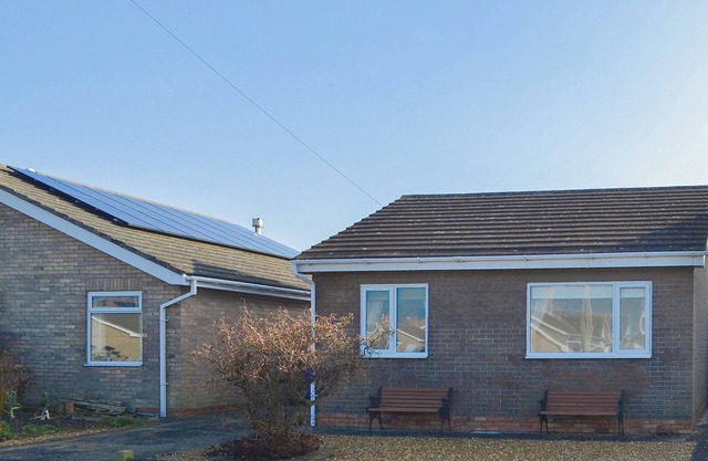 Modern accommodation with sun room and patio overlooking a small lake.