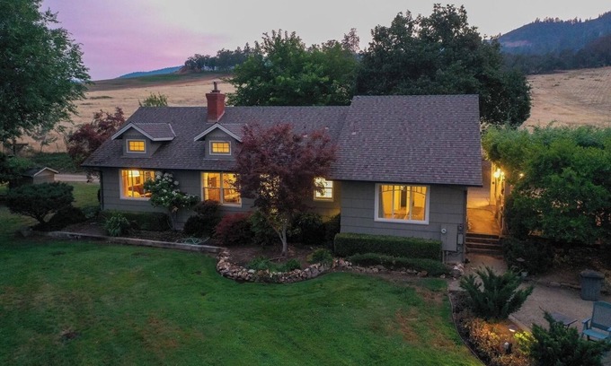 Medford Cottage | Wake to breathtaking sunrises over the rolling hills! Relax by the fire under the stars, & savor sunset dinners beneath fragrant wisteria pergola. Surrounded by wineries and minutes from historic Jacksonville, this retreat blends charm & convenience
